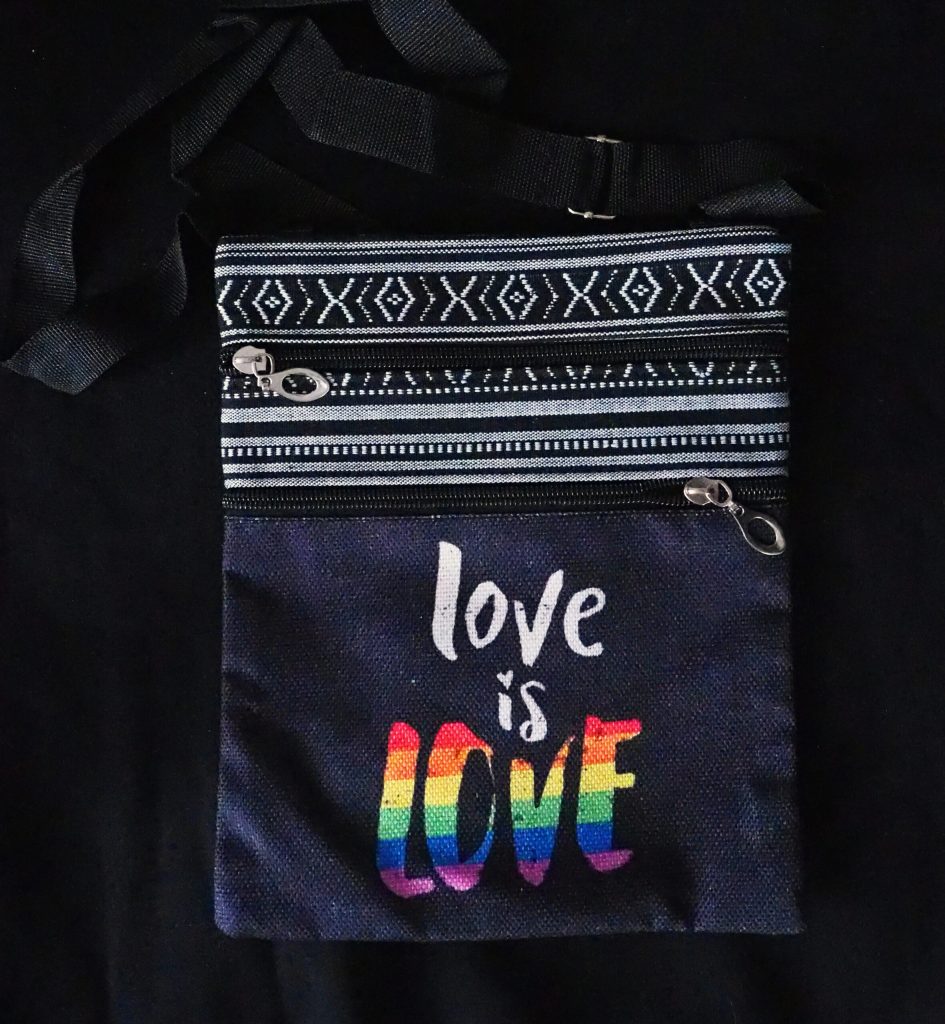 Mørkegrå, middels stor veske med praktiske lommer og teksten "Love is love"