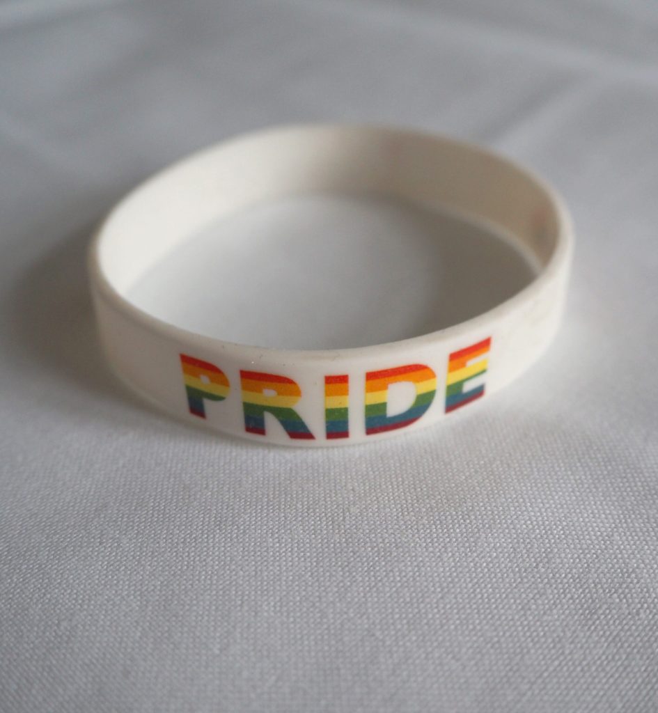 Hvitt silikonarmbånd med teksten LOVE / PRIDE.